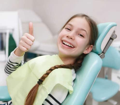 Young girl giving thumbs up in dental chair at Shelton Dental Excellence office